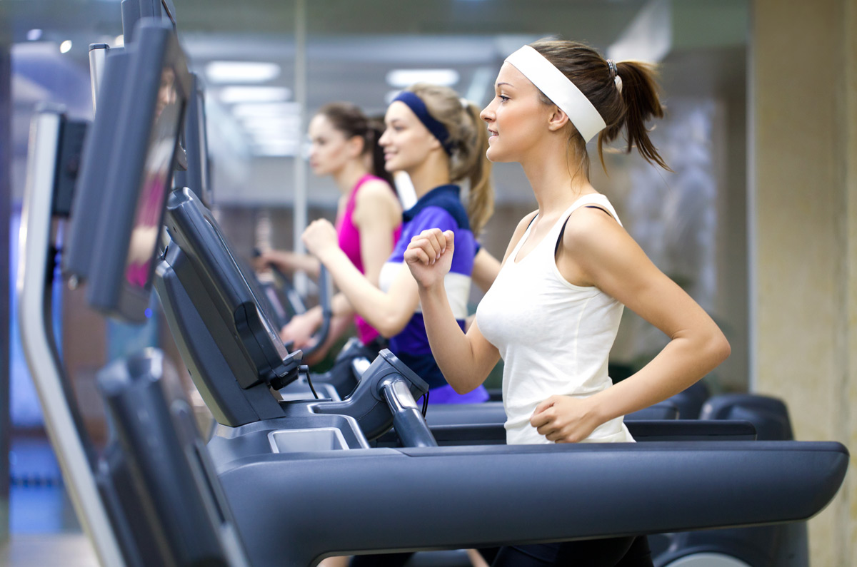 Women running on treadmills in a fitness center.